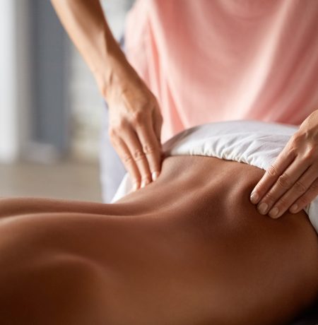 Close up shot of a professional masseuse doing massage with forearms and cubits for male client. Young man relaxing receiving facial massage at the spa center. Relaxation therapy resort recreation.